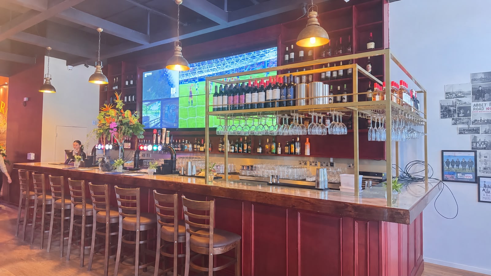 The long bar at Tavern Co. Social with brass wine shelving and big screens behind