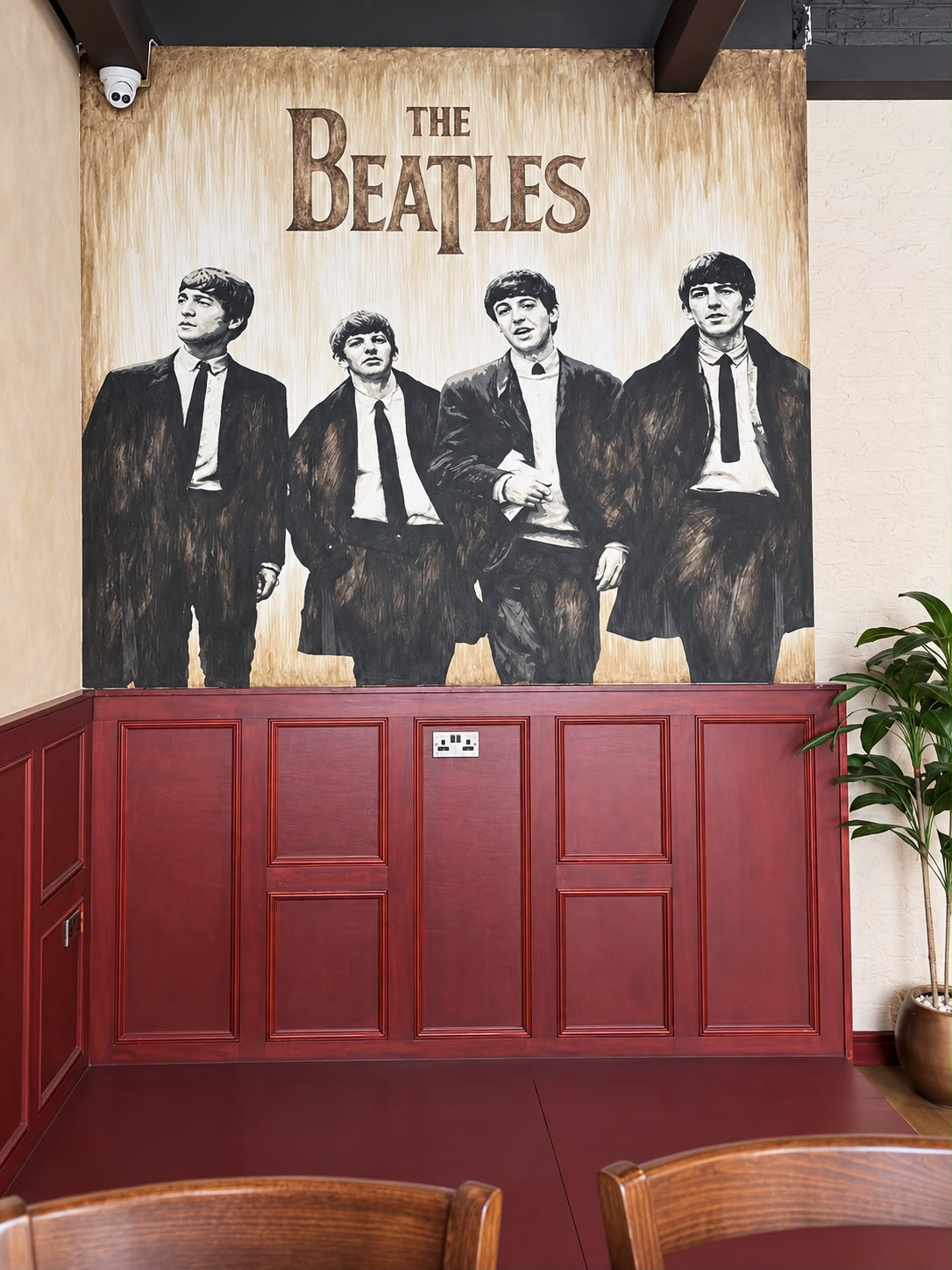 A hand-painted Beatles mural above red wood panelling inside Tavern Co. Social